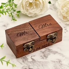 two wooden boxes sitting on top of a marble counter next to flowers and greenery