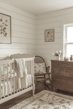 a baby's room with a crib, rocking chair and dresser in black and white