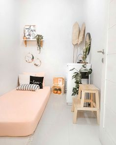 a room with a bed, stool and plants