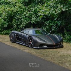 a black sports car parked on the side of a road next to trees and bushes