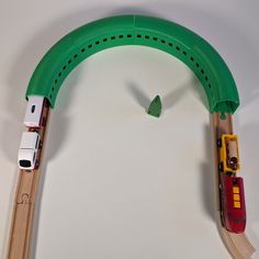 a toy train set with wooden tracks and cars on the track, including a green arch