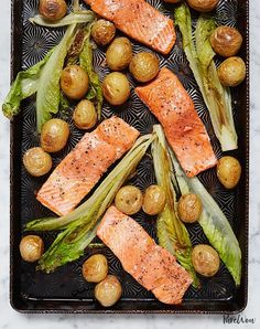 salmon, potatoes and broccoli on a baking sheet with some garnish