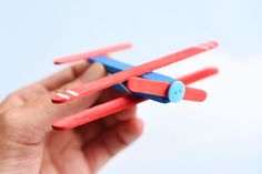 a hand holding a red and blue toy airplane