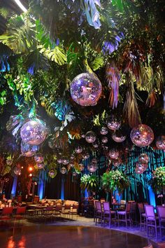 a room filled with lots of disco balls and plants hanging from it's ceiling