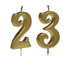 two gold birthday candles with the number 2 on them and one candle in the shape of numbers