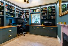 a home office with built - in bookshelves, desk and computer monitor on the far wall