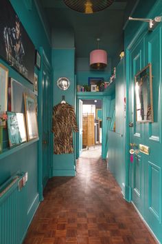 the hallway is painted teal and has pictures hanging on the walls, along with wooden flooring