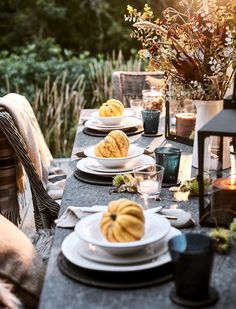 an outdoor table set with plates and candles