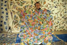 a man standing in front of a large pile of colorful paper butterflies on the ground