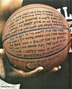 a person holding a basketball in their hands with writing on the bottom half of it