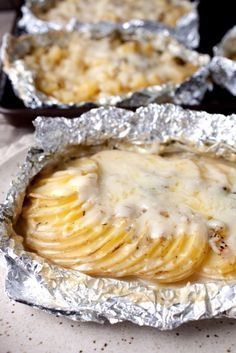 baked potatoes covered in melted cheese on top of tin foil