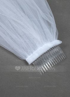 a comb with white tulle attached to it on top of a gray tablecloth