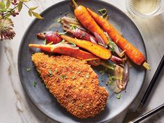 a plate topped with chicken, carrots and radishes on top of a table