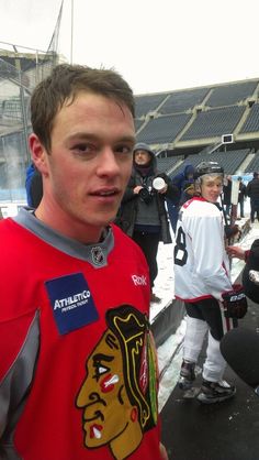 a man standing in front of an ice rink wearing a red jersey with the chicago black hawks on it