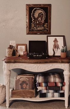 a white table topped with lots of pillows next to a painting and other items on top of it