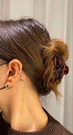 a woman with her hair in a bun has two small hoops attached to the back of her ear