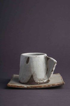 a white cup and saucer sitting on top of a wooden plate with a gray background