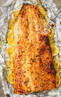 a piece of salmon on foil with lemons and herbs