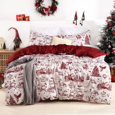 a bed with red and white comforter next to a christmas tree on the floor