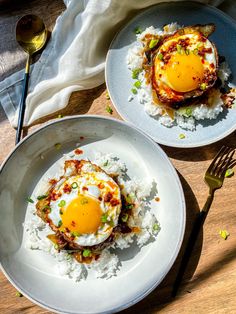 two plates filled with food on top of a wooden table next to utensils