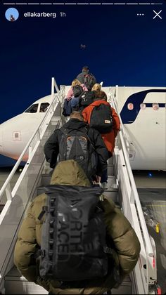 people are boarding an airplane at night on the tarmac with backpacks attached to their backs