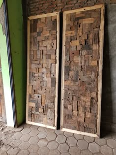 two wooden doors sitting next to each other on a brick floor in front of a green wall