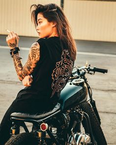 a woman sitting on top of a motorcycle with her arm wrapped around the handlebars