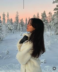 a woman is standing in the snow with her arms crossed and looking up into the sky