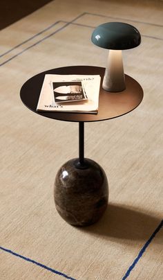 a small table with a lamp on it and a magazine sitting on top of it