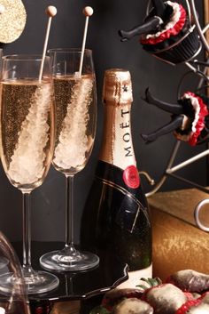 two champagne flutes are sitting next to an assortment of pastries on a platter