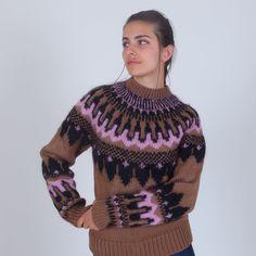 a woman wearing a brown and pink sweater looking up at the sky with her hands on her hips