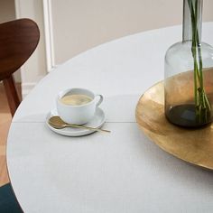 a cup of coffee sits on a saucer next to a vase with flowers in it