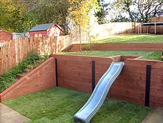 a backyard with a slide in the middle and grass on the ground next to it