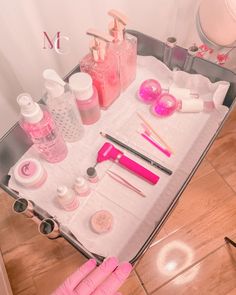 a table with pink items on it in the bathroom and toiletries laid out next to each other