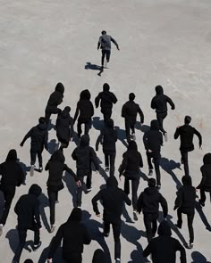 a group of people in black hoodies are skateboarding on the snow covered ground