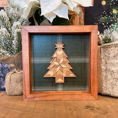 a wooden christmas tree in a frame on a table