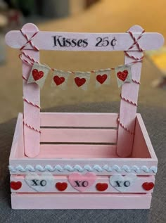 a pink wooden box with hearts on it and a sign that says kisses 25 cents