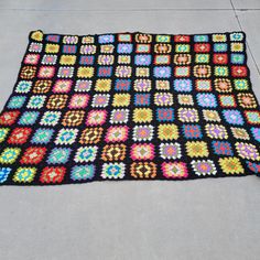 a crocheted blanket is laying on the ground