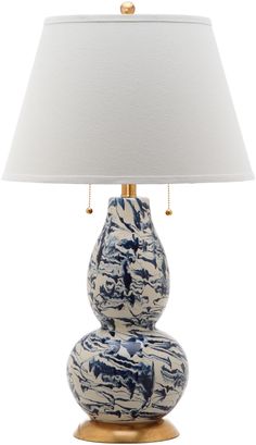 a blue and white vase with a lamp on it's side, sitting on a gold base