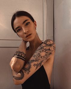 a woman with tattoos on her arm posing for the camera