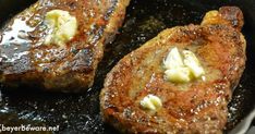 two steaks cooking in a skillet with butter and sauce on them, ready to be eaten