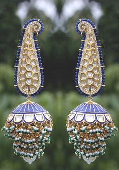 Blue enamel meenakari handpainted chandbaali featuring glass kundan work, cubic zirconia studs, pearl embellishments and plated with 22kt gold. These pretty earrings are a perfect match to all things pastels. The earring features pretty floral motif in glass kundan work and delicate cubic zirconia. The chandbali are embellished with high grade shell pearls. These earrings are handpainted by artisans of Kashmir who are famous for papier-mache artwork. Detailed hand painting alongside studded kund Festive Blue Tilla Jhumkas, Blue Temple Jewelry Jhumkas Gift, Blue Cutdana Earrings For Wedding, Blue Temple Jewelry Earrings For Festive Occasions, Blue Cutdana Wedding Earrings, Blue Chandbali Jewelry With Cutdana, Blue Chandbali Jewelry With Cutdana Detail, Blue Chandbali Jewelry With Meenakari, Blue Tilla Jhumkas For Gift