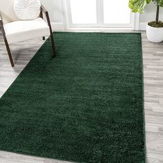 a green rug in a living room with a chair and potted plant on the floor