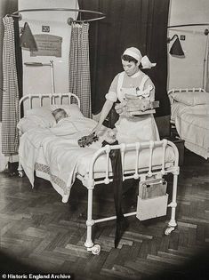 an old black and white photo of a nurse tending to a child in a hospital bed