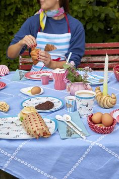 a woman sitting at a picnic table with food on it and candles in front of her