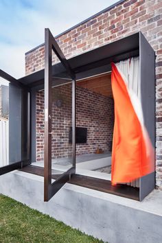 an orange and white flag is hanging on the outside of a brick building with glass doors