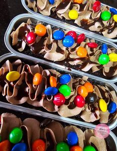 two tins filled with candy and candies on top of a black table next to each other