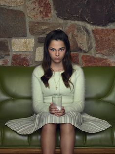 a woman sitting on a green couch holding a cup