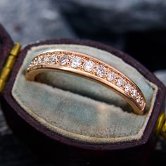 a gold ring with diamonds is sitting in a velvet case