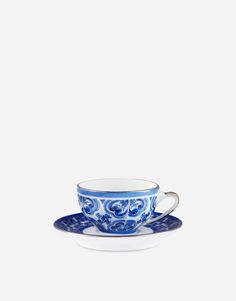 a blue and white tea cup with saucer on a plate against a white background